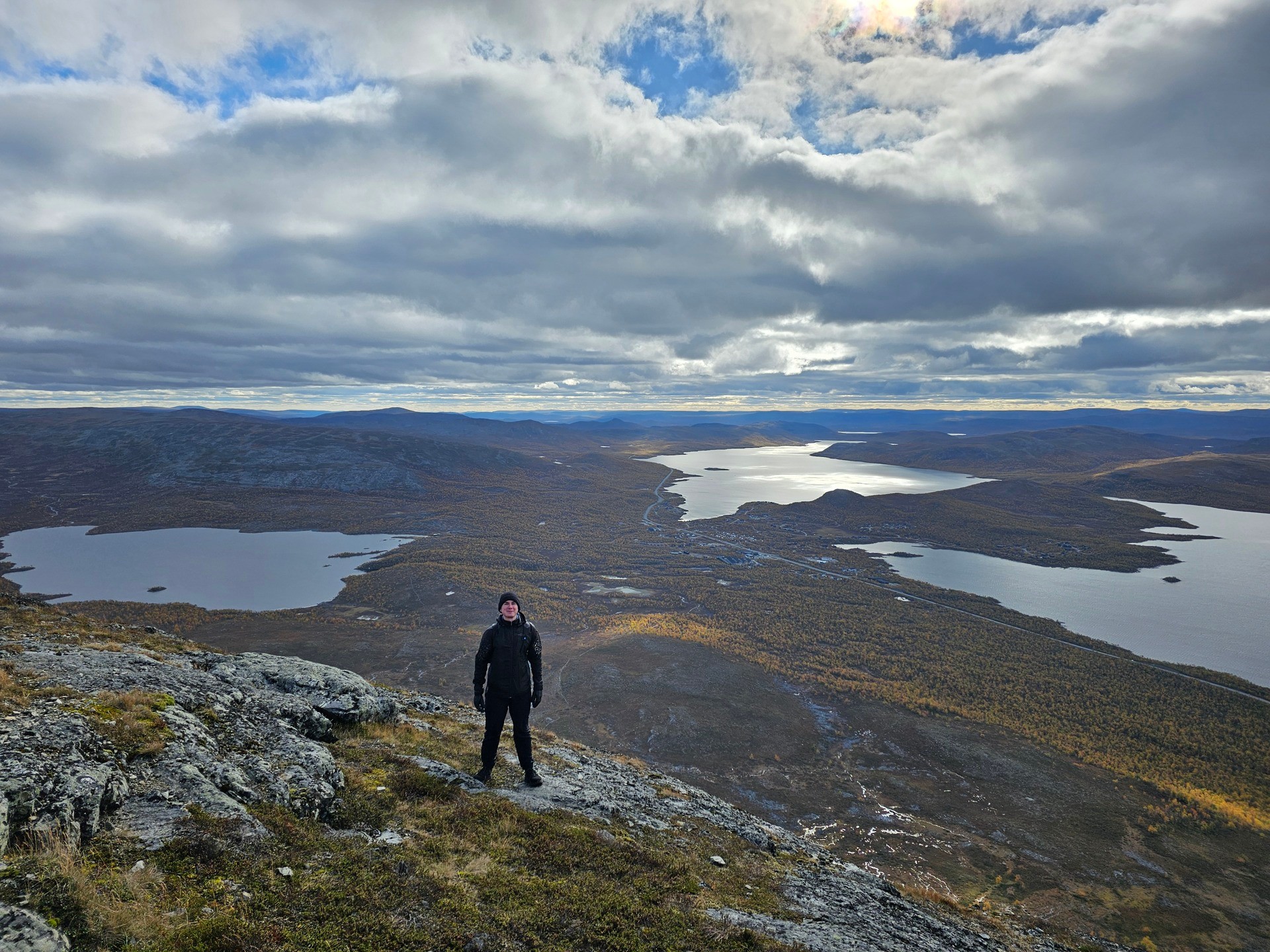 Jere standing on Saana Fell above lakes and autumn-colored Lapland